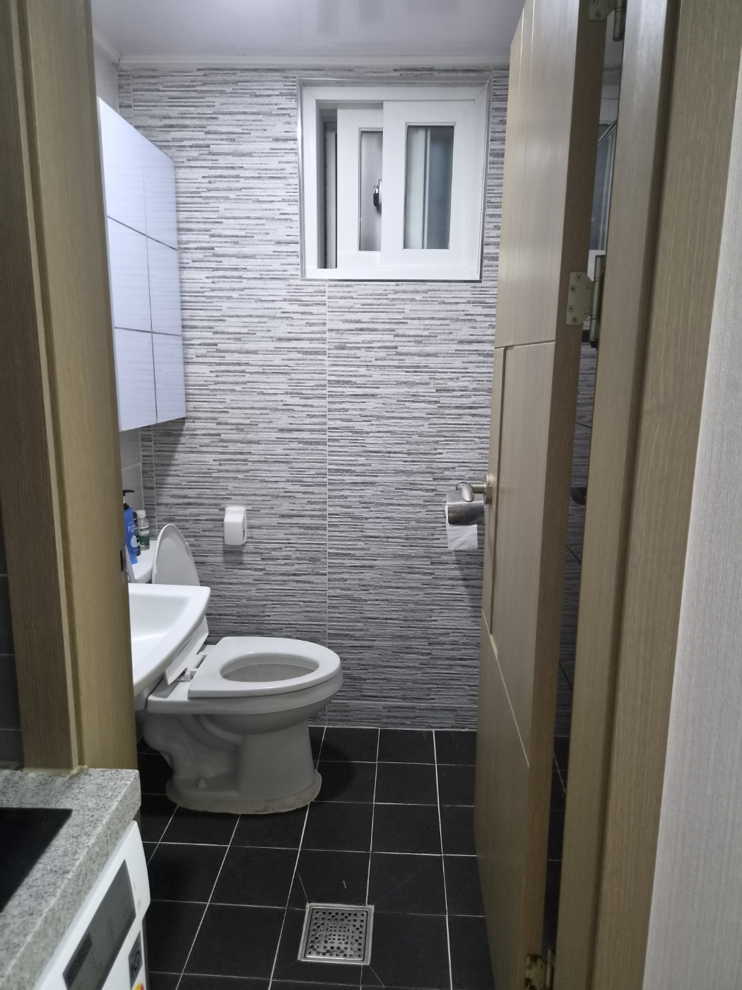 The bathroom of my studio seen from the door, with the toilet, the sink and the window